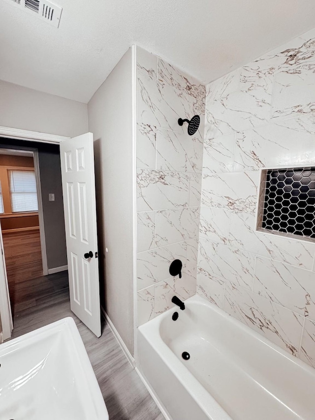 bathroom with wood-type flooring and tiled shower / bath