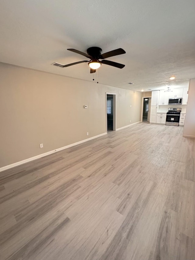 unfurnished living room featuring ceiling fan, a textured ceiling, and light wood-type flooring