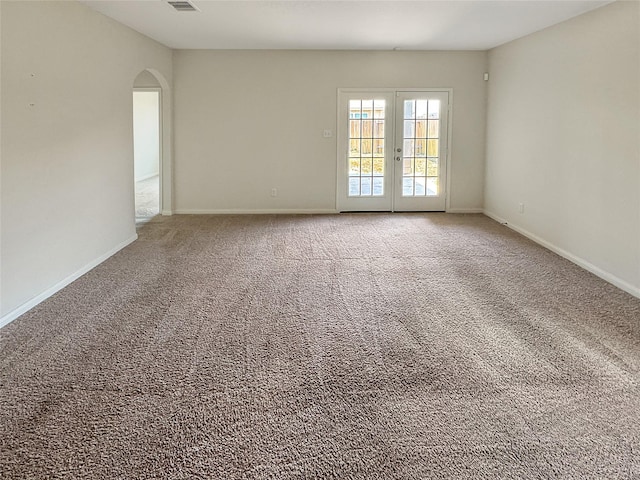 carpeted spare room featuring french doors