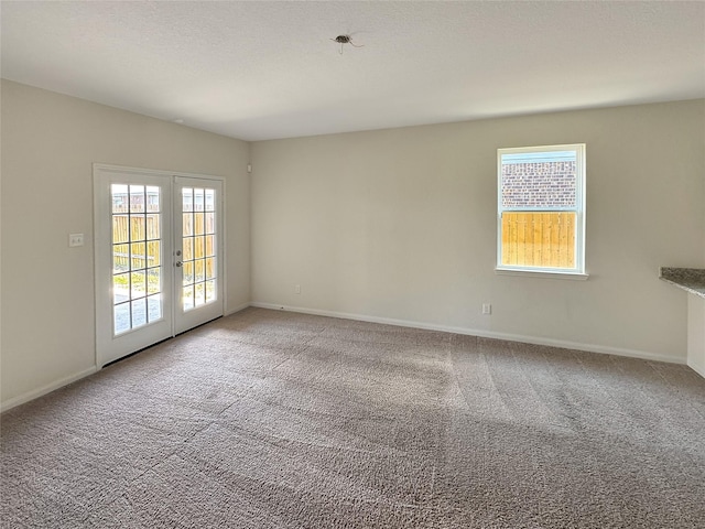 spare room with carpet flooring, a wealth of natural light, and french doors