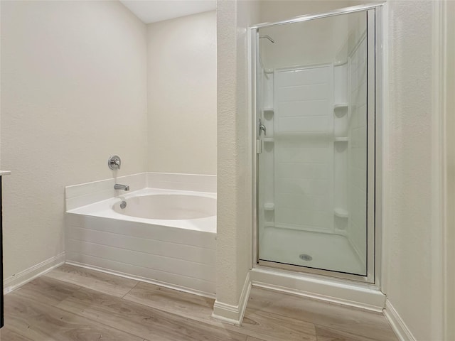 bathroom featuring plus walk in shower and hardwood / wood-style flooring