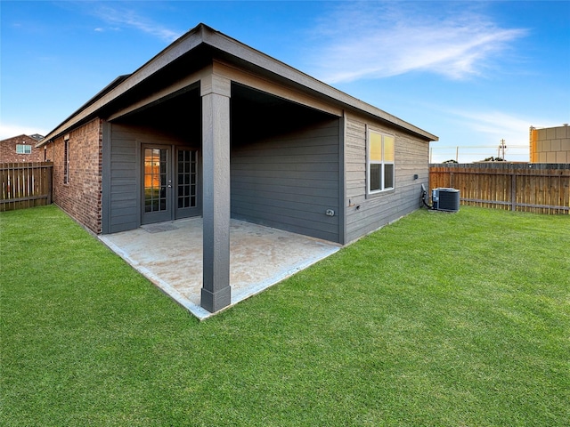 rear view of house featuring cooling unit, a patio area, and a lawn