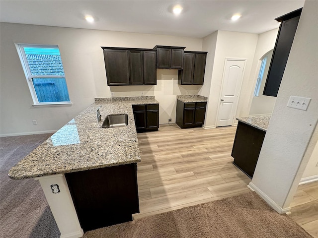 kitchen with light stone countertops, kitchen peninsula, and sink