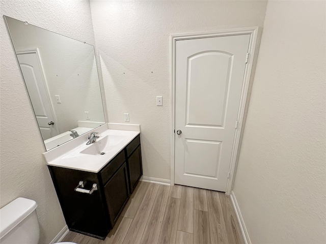 bathroom featuring hardwood / wood-style flooring, vanity, and toilet