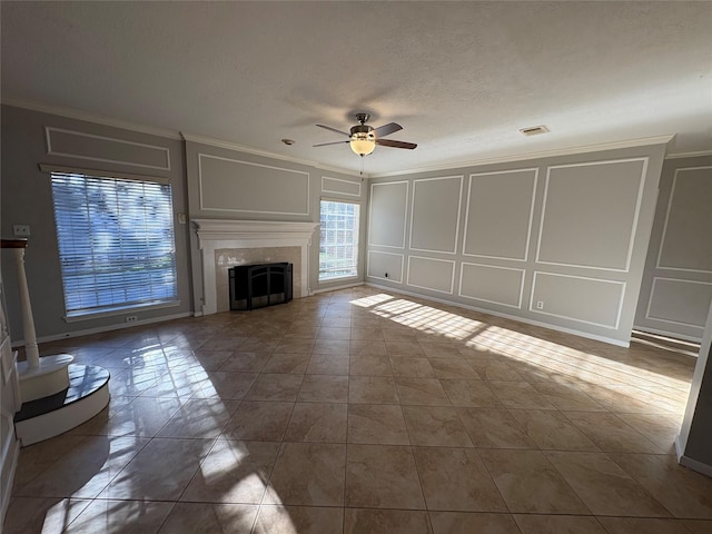 unfurnished living room with crown molding, dark tile patterned floors, ceiling fan, and a textured ceiling