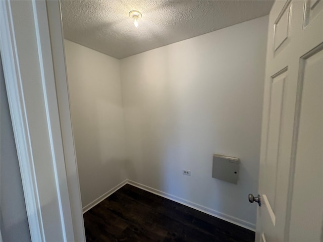 clothes washing area with a textured ceiling and dark hardwood / wood-style floors