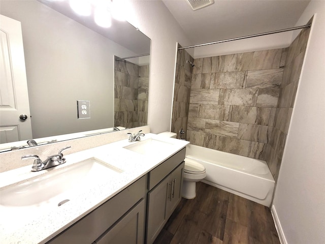 full bathroom featuring vanity, hardwood / wood-style floors, tiled shower / bath combo, and toilet