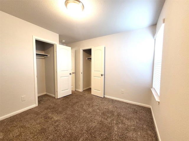 unfurnished bedroom featuring a closet and dark carpet