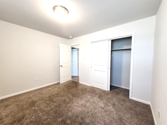 unfurnished bedroom featuring a closet and dark carpet