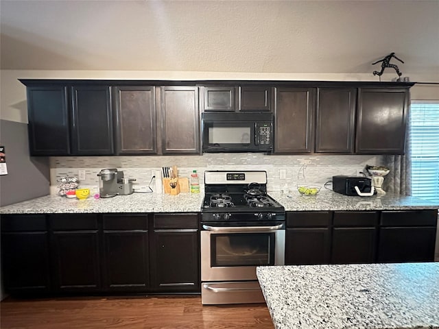 kitchen featuring light stone countertops, decorative backsplash, gas stove, and dark hardwood / wood-style floors