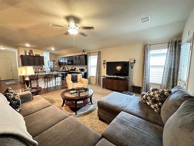 living room featuring a textured ceiling, light wood-type flooring, and ceiling fan