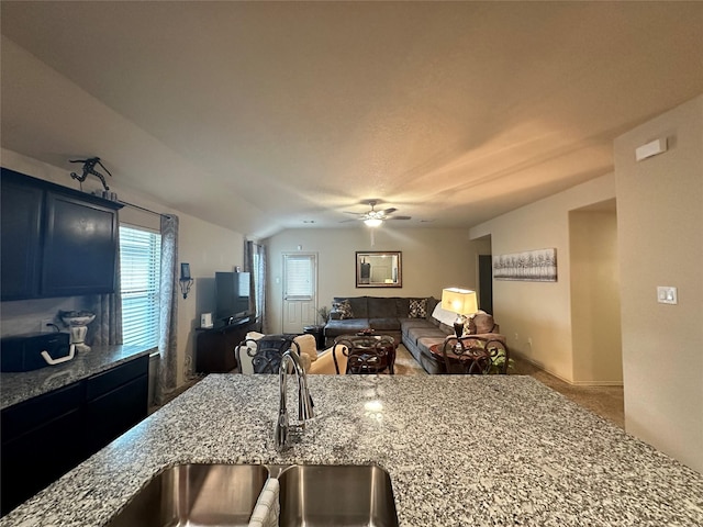 kitchen with light stone countertops, ceiling fan, lofted ceiling, and sink