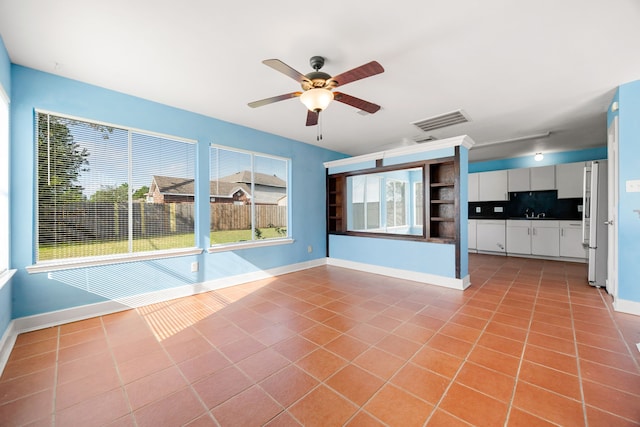 unfurnished living room with light tile patterned floors, ceiling fan, and sink