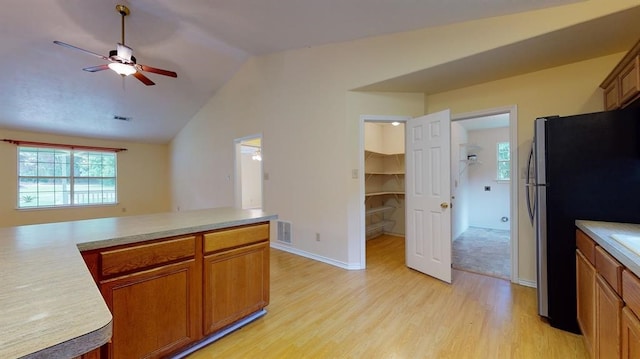 kitchen with stainless steel refrigerator, ceiling fan, vaulted ceiling, and light wood-type flooring