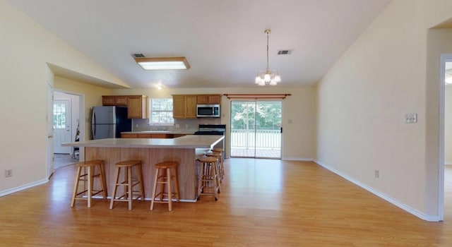 kitchen with stainless steel appliances, a notable chandelier, decorative light fixtures, vaulted ceiling, and decorative backsplash