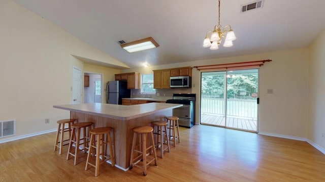 kitchen featuring light wood-type flooring, tasteful backsplash, stainless steel appliances, pendant lighting, and lofted ceiling