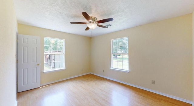 spare room featuring ceiling fan, light wood-type flooring, and a textured ceiling