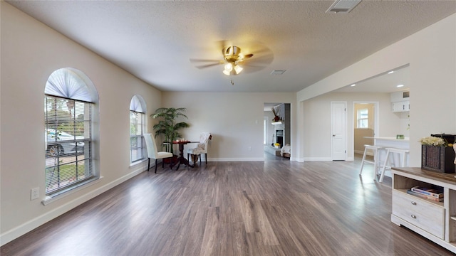 sitting room featuring a textured ceiling, a wealth of natural light, dark wood-type flooring, and ceiling fan