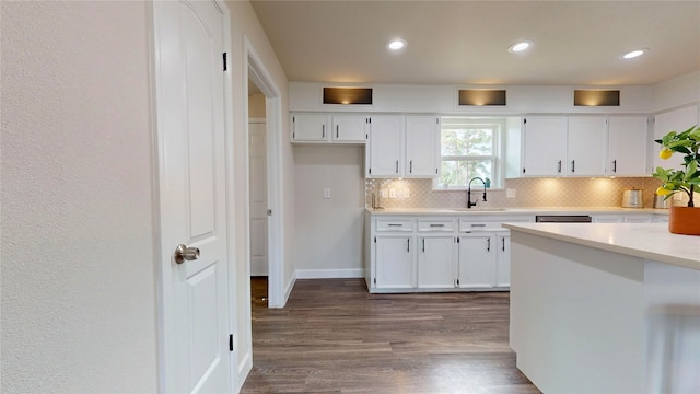 kitchen with tasteful backsplash, dark hardwood / wood-style flooring, white cabinetry, and sink