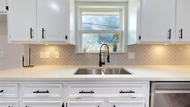 kitchen with decorative backsplash, sink, white cabinets, and stainless steel dishwasher