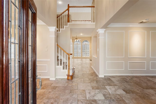 entrance foyer featuring decorative columns, ceiling fan, and crown molding