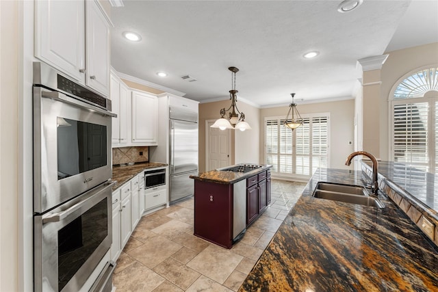 kitchen with decorative backsplash, sink, built in appliances, a center island, and white cabinetry