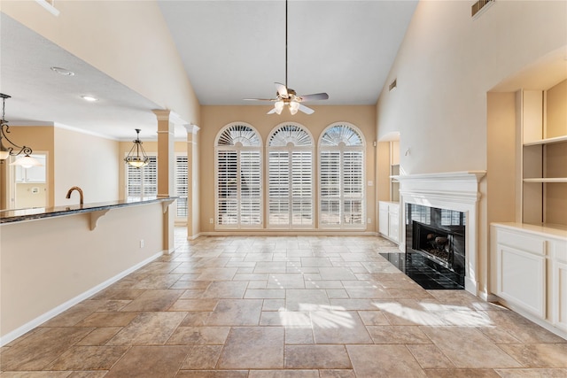 unfurnished living room featuring ceiling fan with notable chandelier, lofted ceiling, and a fireplace