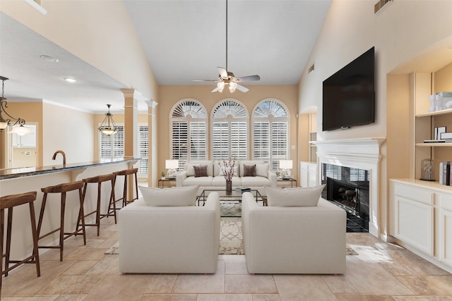 living room featuring ceiling fan with notable chandelier, a high end fireplace, and vaulted ceiling