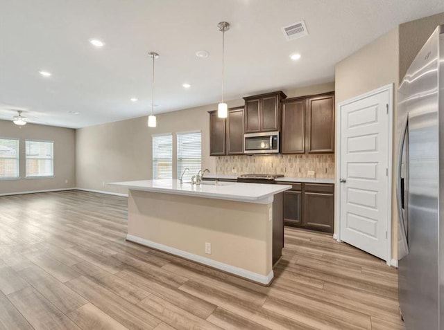 kitchen featuring appliances with stainless steel finishes, tasteful backsplash, dark brown cabinets, ceiling fan, and hanging light fixtures