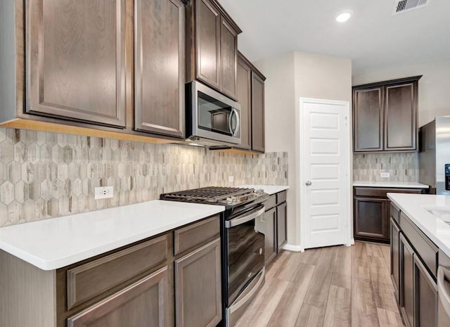 kitchen with backsplash, light hardwood / wood-style floors, dark brown cabinetry, and stainless steel appliances