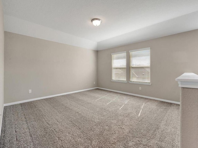 carpeted spare room with a textured ceiling and lofted ceiling