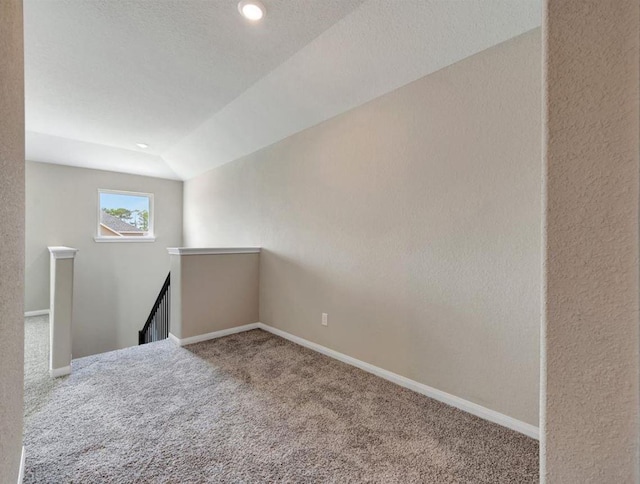 empty room featuring carpet, a textured ceiling, and lofted ceiling