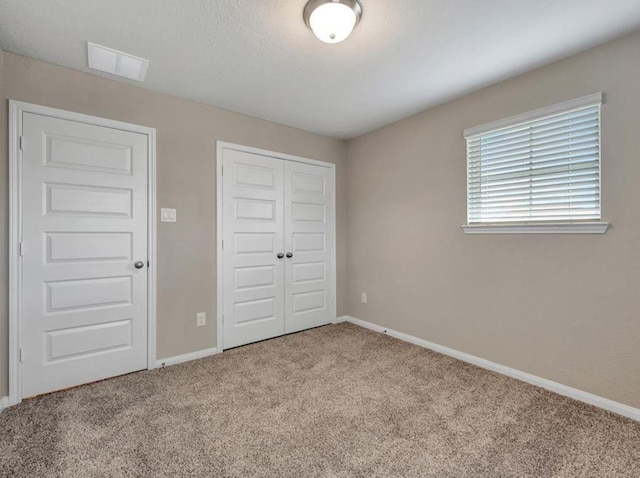 unfurnished bedroom featuring light carpet and a closet