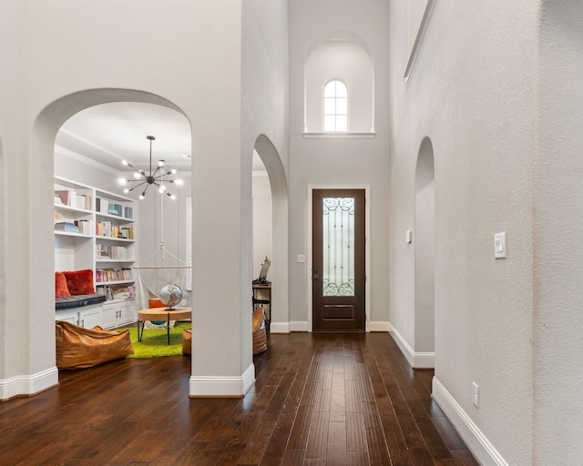 entrance foyer featuring dark hardwood / wood-style floors, a high ceiling, and an inviting chandelier