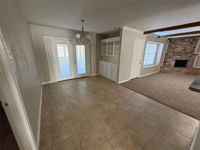 unfurnished living room featuring french doors, a brick fireplace, beam ceiling, light colored carpet, and a chandelier