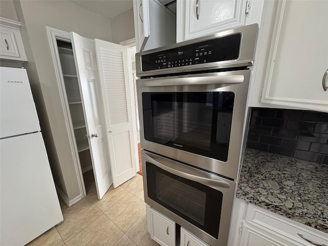 kitchen with backsplash, white cabinets, double oven, stone countertops, and white fridge