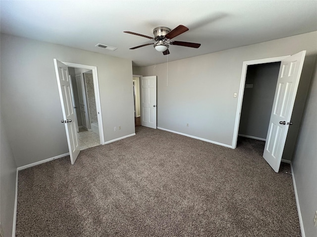 unfurnished bedroom featuring ensuite bath, ceiling fan, and dark carpet