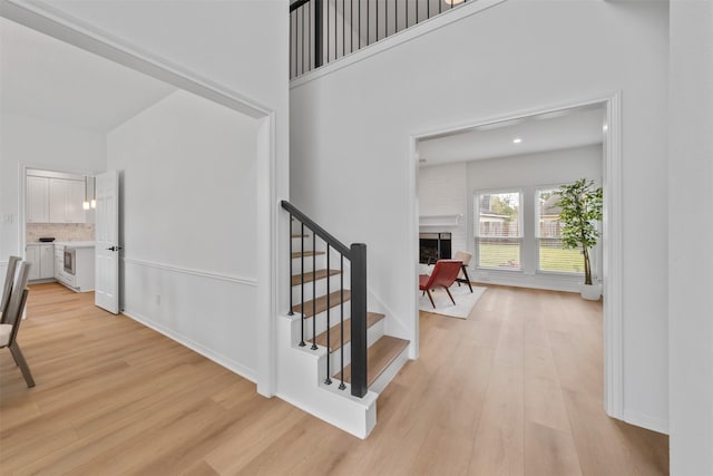 stairs featuring hardwood / wood-style floors, a large fireplace, and a high ceiling