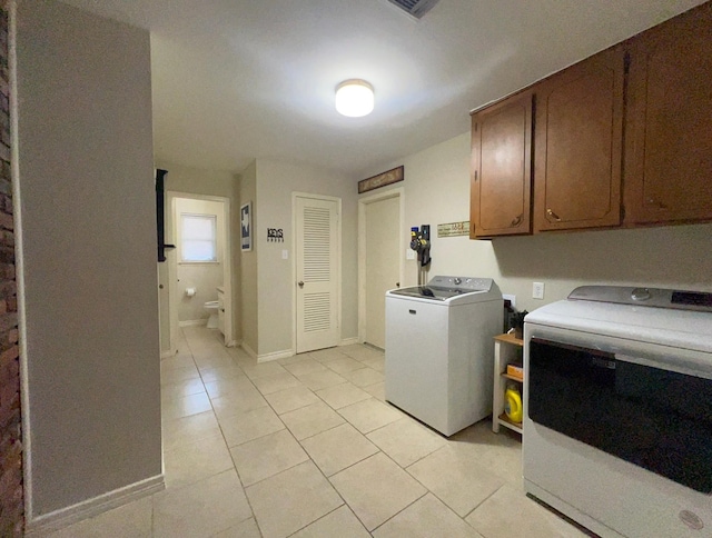 laundry area featuring light tile patterned flooring, separate washer and dryer, and cabinets