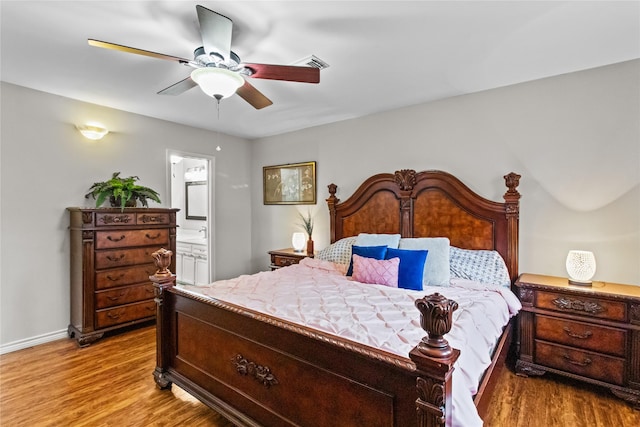 bedroom featuring ceiling fan, light hardwood / wood-style flooring, and connected bathroom