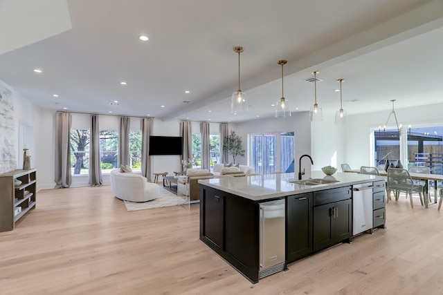 kitchen featuring a kitchen island with sink, sink, hanging light fixtures, light hardwood / wood-style floors, and a chandelier