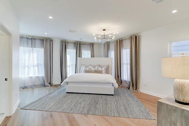 bedroom featuring light hardwood / wood-style flooring, multiple windows, and a notable chandelier