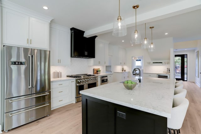 kitchen with sink, high quality appliances, an island with sink, decorative backsplash, and white cabinets