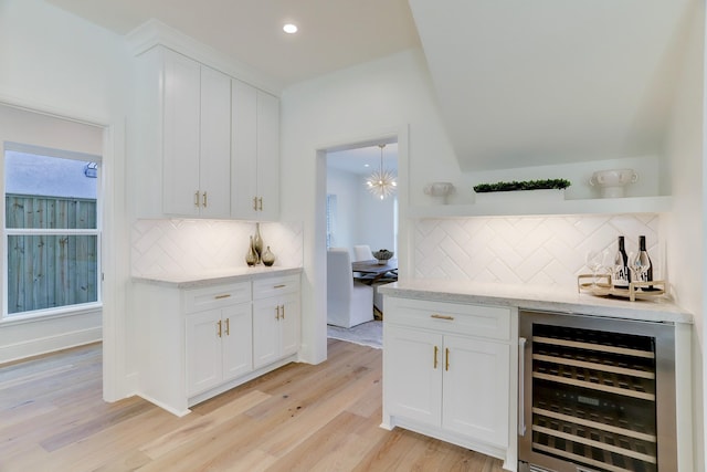 bar featuring backsplash, light hardwood / wood-style flooring, white cabinetry, and beverage cooler