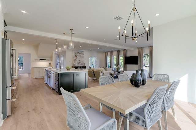 dining room with light wood-type flooring, sink, and a chandelier