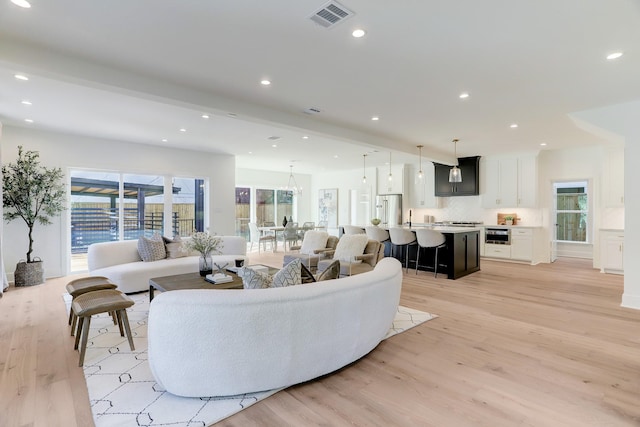 living room with beam ceiling, light wood-type flooring, and sink