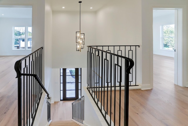 stairway with wood-type flooring and an inviting chandelier