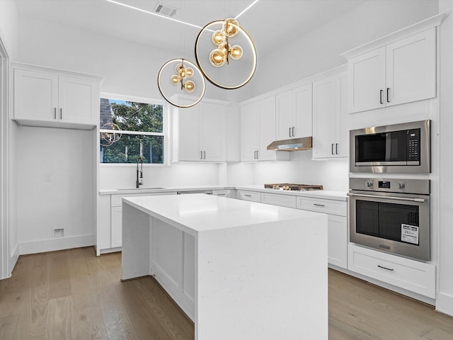 kitchen with a center island, sink, appliances with stainless steel finishes, white cabinets, and light wood-type flooring