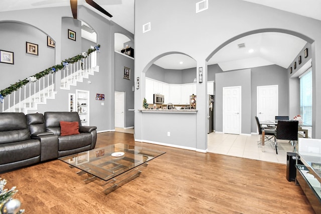 living room featuring a towering ceiling, built in shelves, and light wood-type flooring