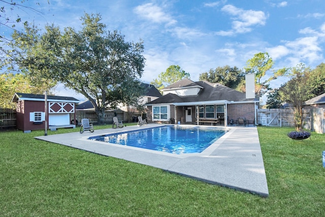 view of swimming pool with a lawn, a patio, and a storage unit